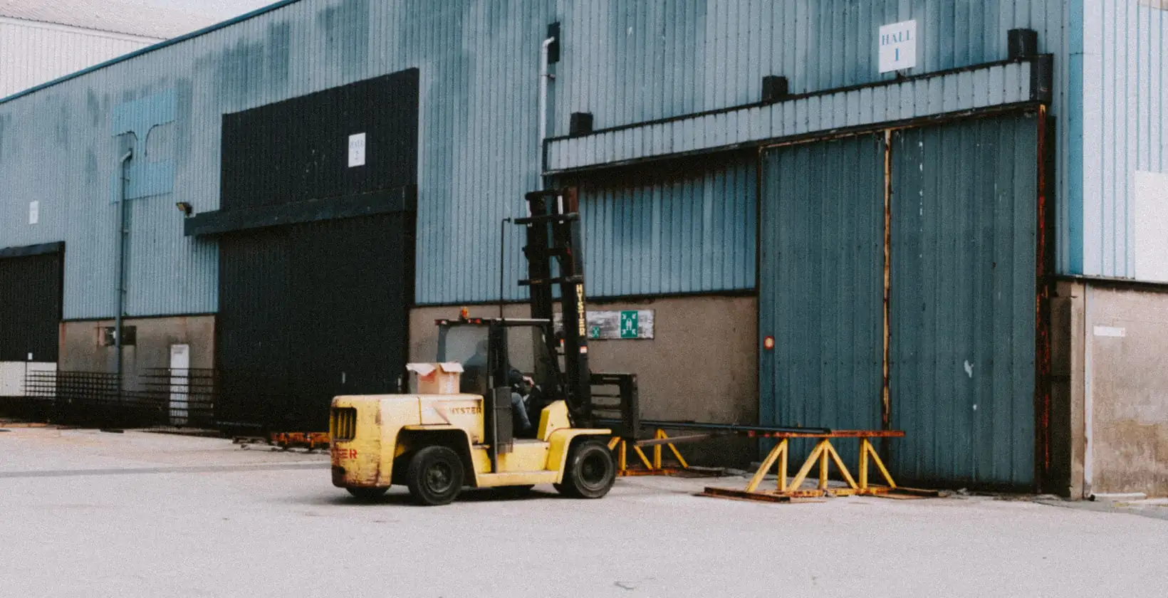 Industrial forklift parked outside a warehouse hall