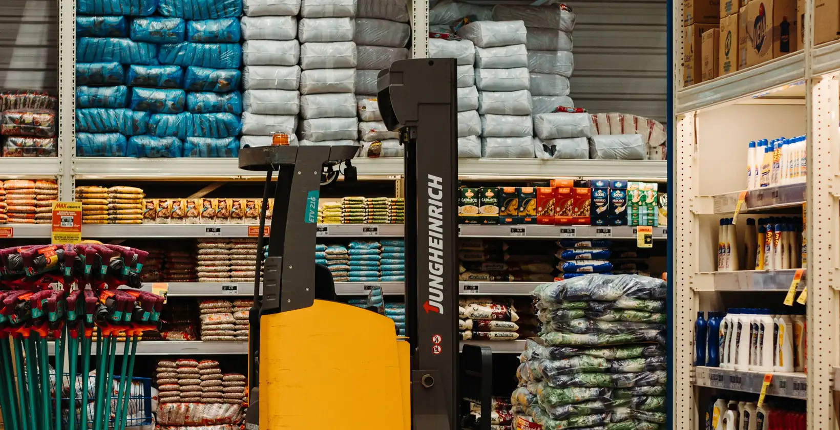 Yellow reach truck parked in a stocked retail warehouse aisle
